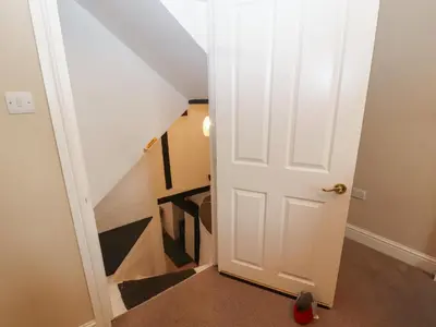a door leading up to a stairwell with a stair at Lillibet Cottage in Keswick