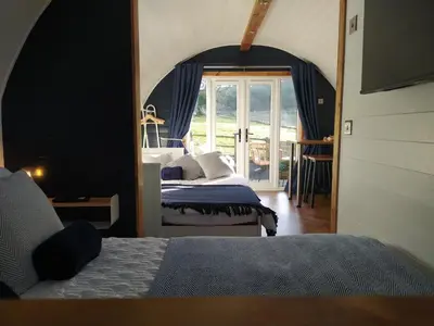 a bedroom with two beds and a large window at little peru luxury pods and alpaca farm in Crosshill
