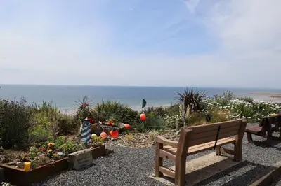 a wooden bench sitting in front of the beach at Tigh Samhradh in Monreith
