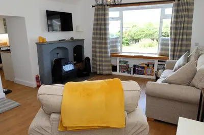 a living room with a couch and a fireplace at Tigh Samhradh in Monreith