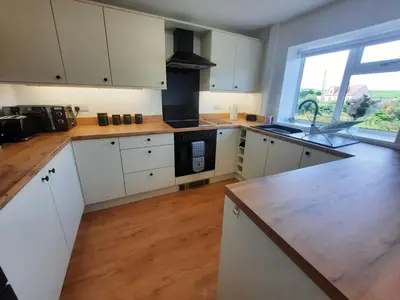 a kitchen with white cabinets and a large window at Tigh Samhradh in Monreith