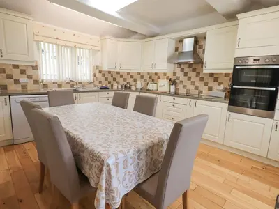 a kitchen with white cabinets and a table with chairs at Hollens Cottage in Ambleside