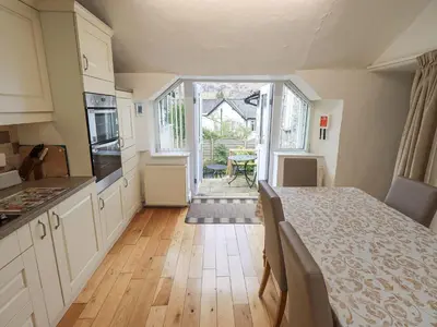 a kitchen with white cabinets and a wooden floor at Hollens Cottage in Ambleside