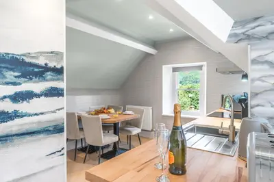 a kitchen and dining room with a table and a wine bottle at Fell215 - Classic loft apartment at The Lairbeck in Keswick in Keswick