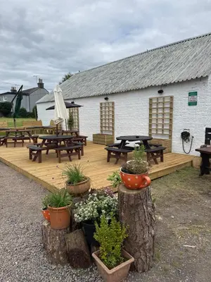 a wooden deck with benches and picnic tables in front of a building at Ecclefechan Hotel in Ecclefechan