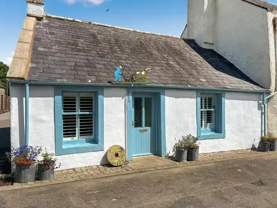 a white and blue house with a blue door at Bruce Cottage in Whithorn