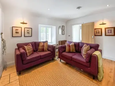 a living room with two purple couches and a rug at Bruce Cottage in Whithorn