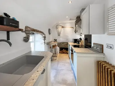 a kitchen with white cabinets and a sink at Bruce Cottage in Whithorn