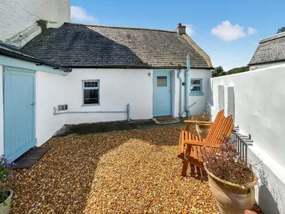 a patio with two chairs in front of a house at Bruce Cottage in Whithorn