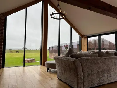 a living room with a couch and large windows at Blencathra Barn in Penrith
