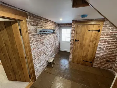 a room with a brick wall and a wooden door at Blencathra Barn in Penrith