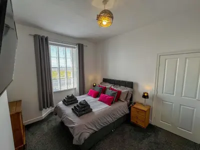 a bedroom with a large bed with pink pillows at North Lodge Retreat Allonby in Maryport