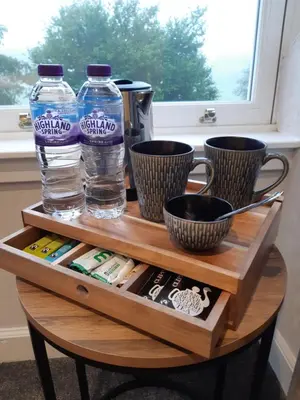 a wooden table with two bottles of water and cups at Burnbank Bed and Breakfast in Moffat