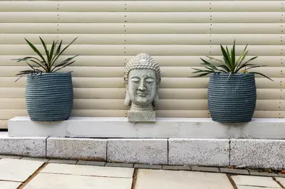 a statue sitting on a bench with two potted plants at Tranquil House with Sea Views in Parton