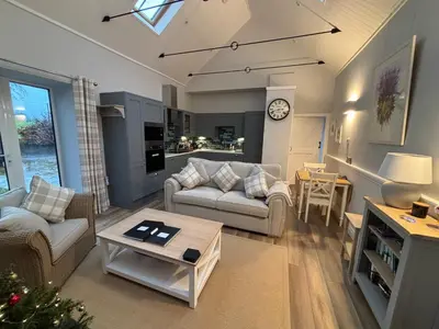 a living room with two couches and a table at Stable Cottage in Lockerbie