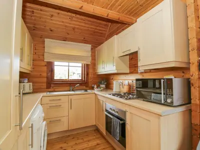 a kitchen with wooden walls and white cabinets at Glenisle in Dalbeattie