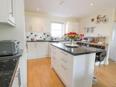 a kitchen with white cabinets and a vase of flowers on a counter at Ptarmigan in Newton Stewart