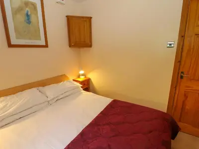 a bedroom with a white bed with a red blanket at Bluebells in Ambleside