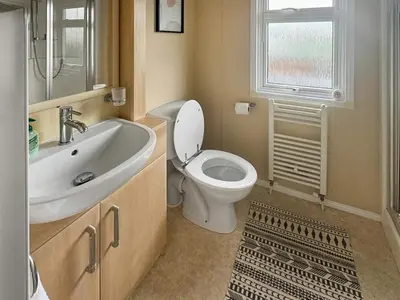 a bathroom with a toilet and a sink and a window at Zion's Retreat in Plumbland