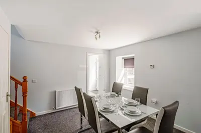 a dining room with a white table and chairs at Auchenlarie Courtyard No 1 in Gatehouse of Fleet