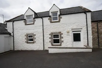 a white brick house with a parking lot at Auchenlarie Courtyard No 1 in Gatehouse of Fleet