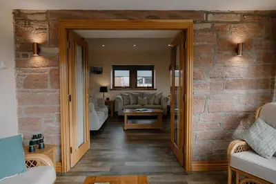 a living room with a brick wall at Country cottage with garden, views & games room in Dumfries