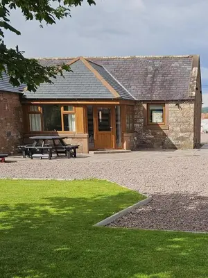 a building with a picnic table in front of it at Country cottage with garden, views & games room in Dumfries