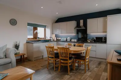 a kitchen and dining room with a table and chairs at Country cottage with garden, views & games room in Dumfries