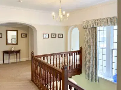 a living room with a staircase and a chandelier at Bank House Longtown, ideal group accommodation with swimming pool & hot tub in Longtown