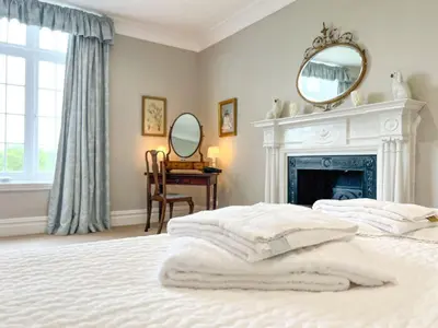 a bedroom with a bed with a fireplace and a mirror at Bank House Longtown, ideal group accommodation with swimming pool & hot tub in Longtown