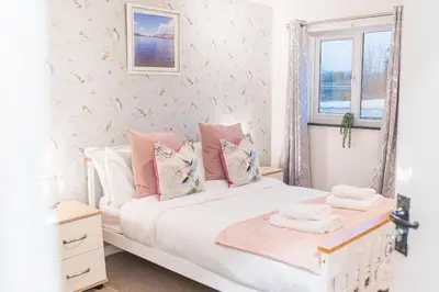 a bedroom with a white bed with pink pillows at 4BR Holiday Home Steps from Keswick Town Centre in Keswick
