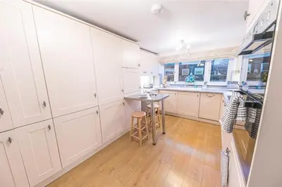 a kitchen with white cabinets and a table in it at 4BR Holiday Home Steps from Keswick Town Centre in Keswick