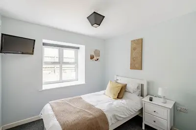 a white bedroom with a bed and a window at Auchenlarie Courtyard No 3 in Gatehouse of Fleet