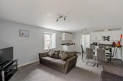 a living room with a couch and a kitchen at Auchenlarie Courtyard No 3 in Gatehouse of Fleet