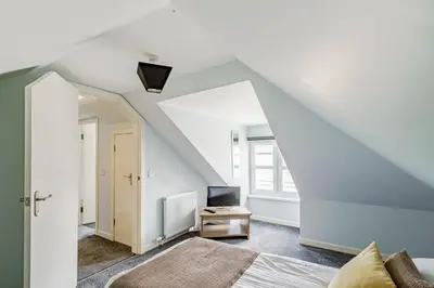 a attic bedroom with a bed and a television at Auchenlarie Courtyard No 3 in Gatehouse of Fleet