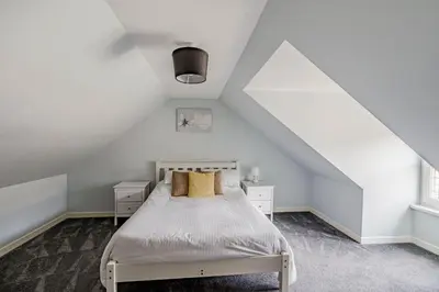 a white bedroom with a bed in a attic at Auchenlarie Courtyard No 3 in Gatehouse of Fleet