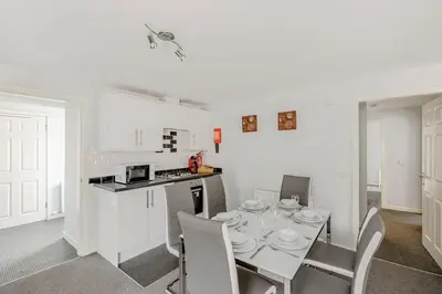 a white kitchen with a table and chairs in a room at Auchenlarie Courtyard No 3 in Gatehouse of Fleet