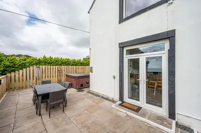 a patio with a table and chairs and a fence at Auchenlarie Farmhouse in Gatehouse of Fleet