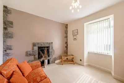 a living room with a couch and a fireplace at Auchenlarie Farmhouse in Gatehouse of Fleet