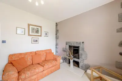 a living room with a couch and a fireplace at Auchenlarie Farmhouse in Gatehouse of Fleet