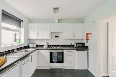 a kitchen with white cabinets and a sink at Auchenlarie Courtyard No 5 in Gatehouse of Fleet