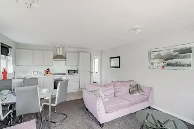 a living room with a pink couch and a kitchen at Auchenlarie Courtyard No 4 in Gatehouse of Fleet