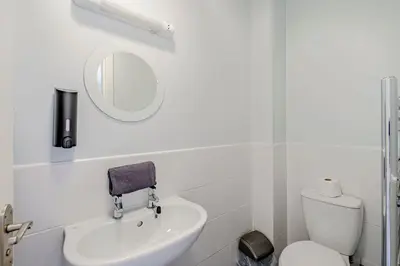 a white bathroom with a sink and a mirror at Auchenlarie Courtyard No 4 in Gatehouse of Fleet
