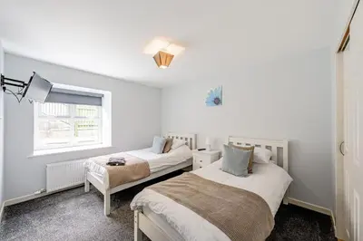 a bedroom with two beds and a window at Auchenlarie Courtyard No 2 in Gatehouse of Fleet