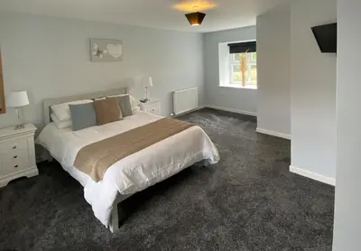 a bedroom with a large bed and a window at Auchenlarie Courtyard No 2 in Gatehouse of Fleet