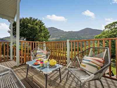 a table and chairs on a deck with mountains in the background at 4 Bed in Buttermere oc-sz090 in Buttermere