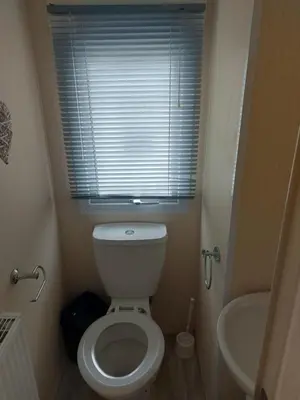 a small bathroom with a toilet and a sink at Victoria's Caravans in Ayr