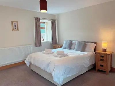 a bedroom with a white bed with two hats on it at Dungavel Cottage in Roberton