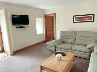 a living room with a couch and a table at Dungavel Cottage in Roberton