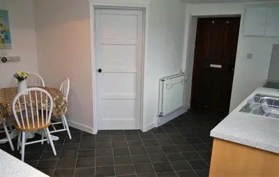 a kitchen with a table and chairs and a door at Swallow Cottage in Dalbeattie